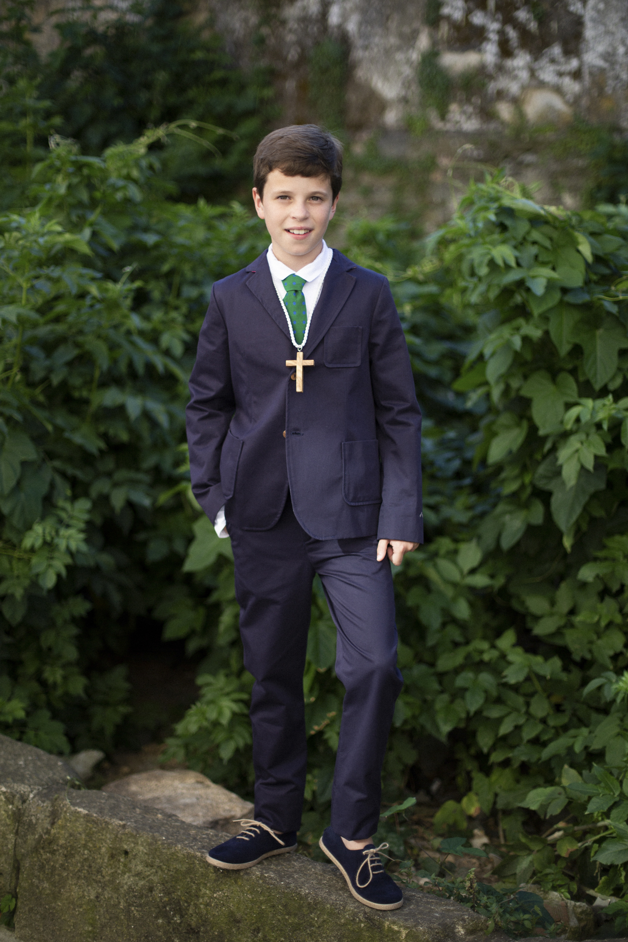 Niño de comunión de pie sobre un muro de piedra