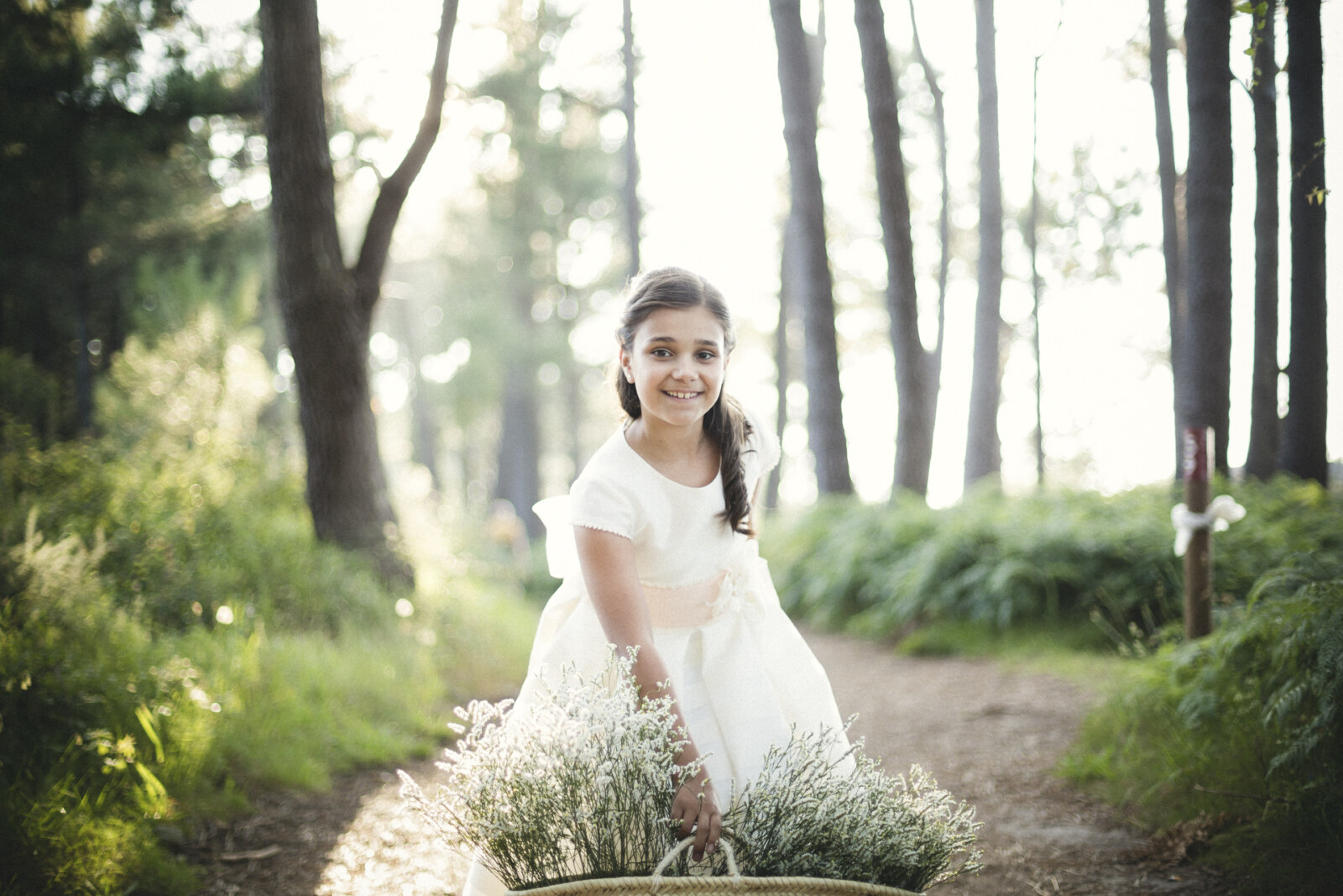 Niña de comunión junto a flores en el bosque