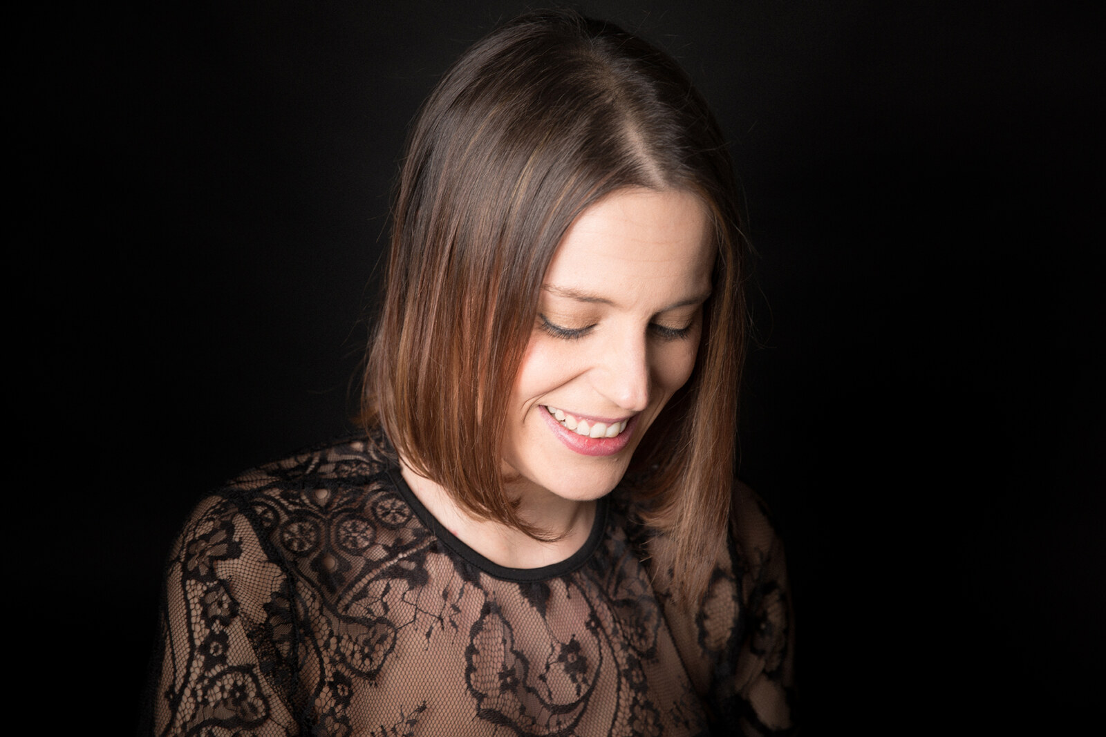 Retrato de mujer embarazada sonriendo con top de encaje, sesión de maternidad en estudio
