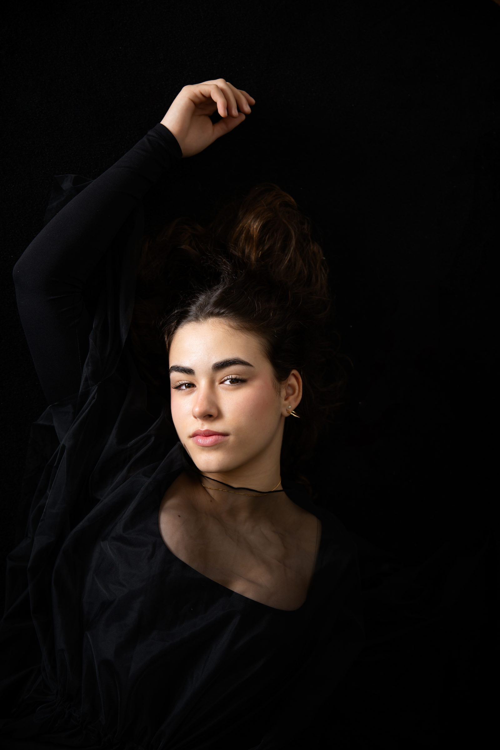 Retrato de estudio con el brazo alzado y la luz recortando el rostro
