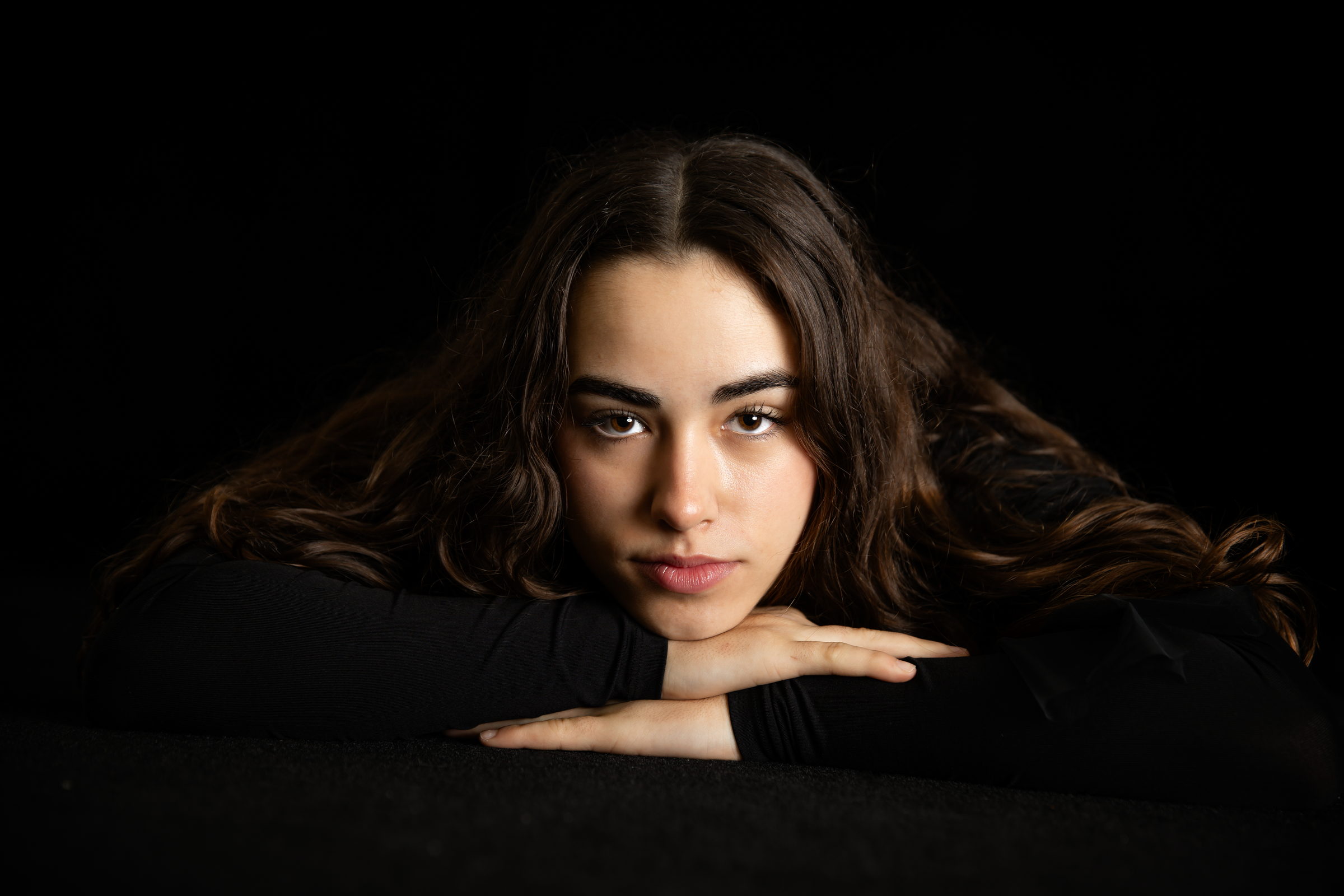 Retrato de estudio de una joven apoyada sobre los brazos, con luz lateral