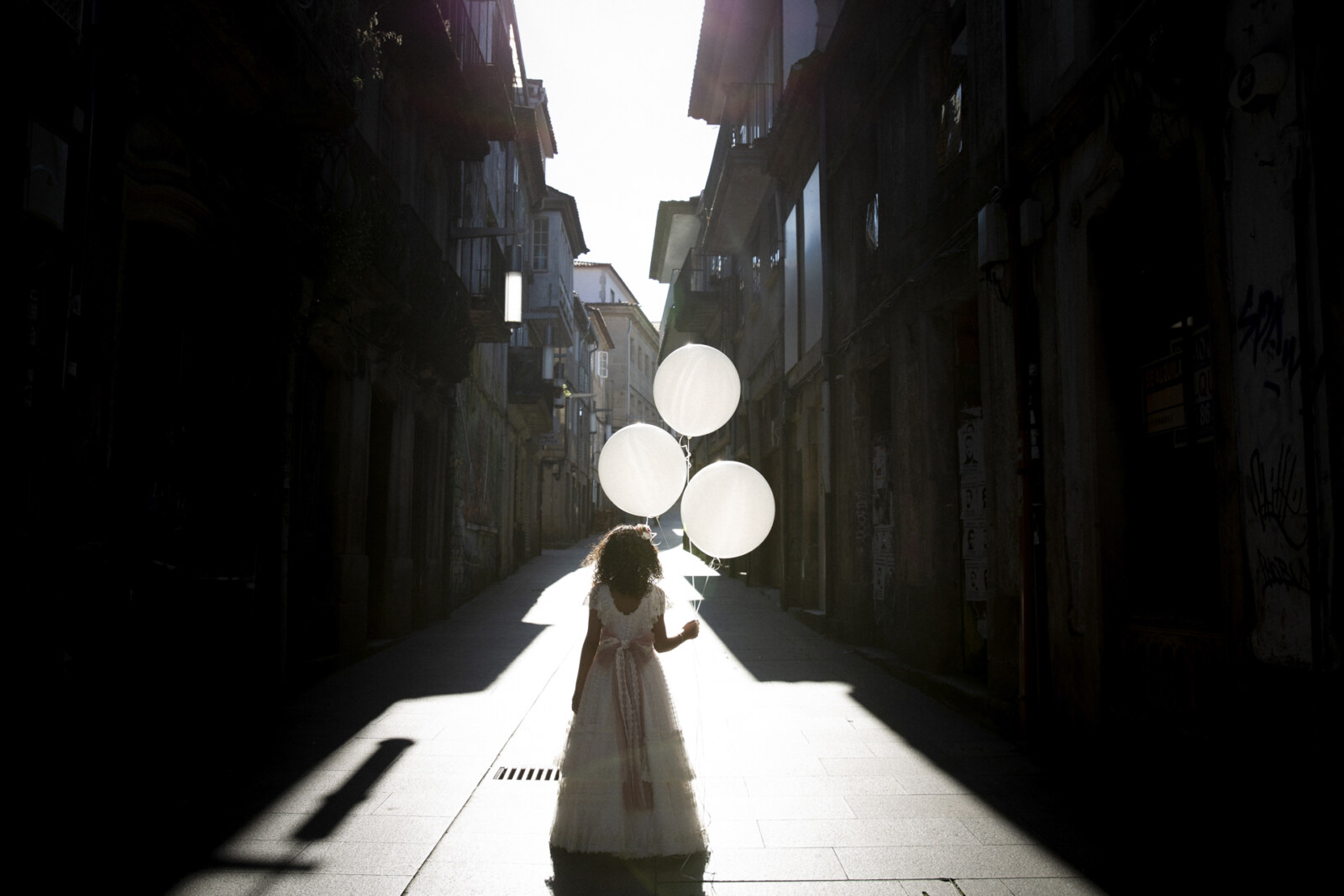 Niña con globos blancos en una calle del casco antiguo de Pontevedra