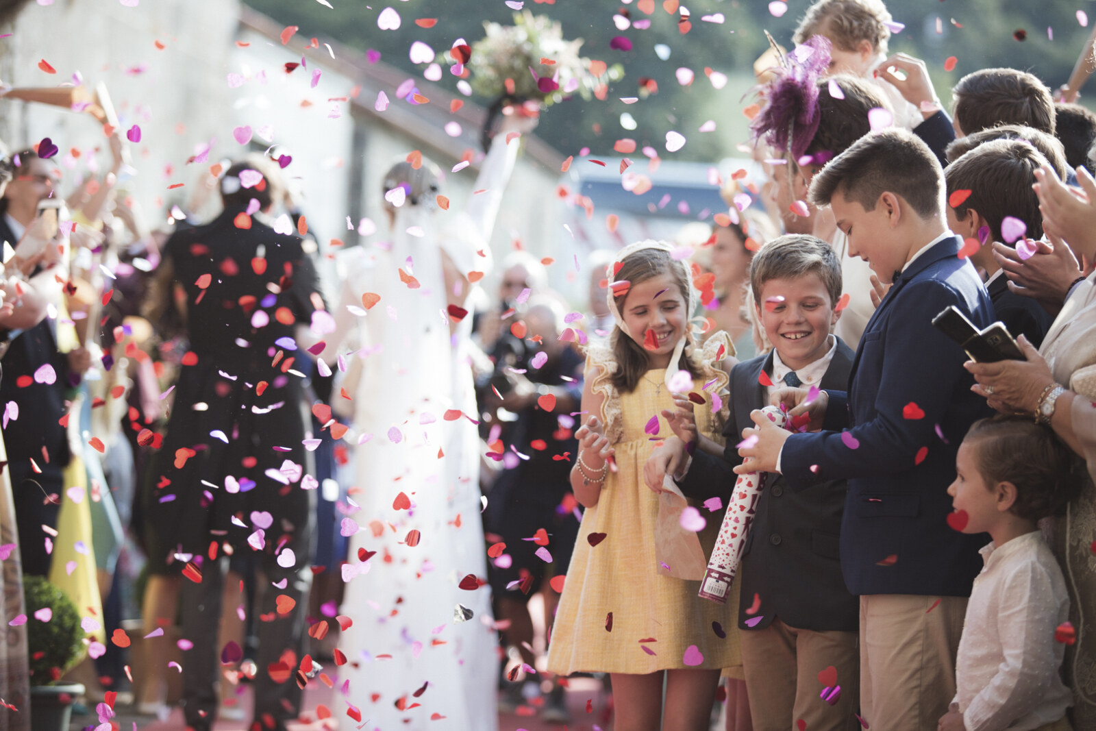Niños lanzando confeti en forma de corazón a la salida de una boda