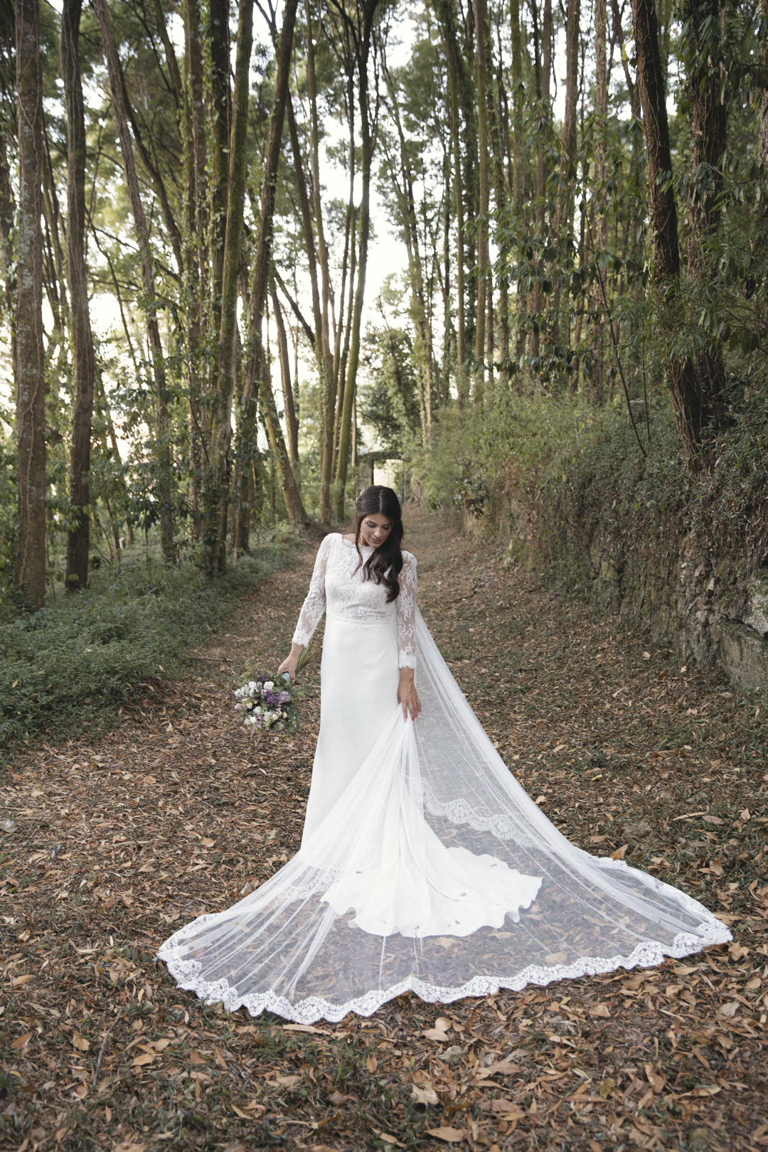 Novia caminando por un camino de bosque con el ramo en la mano