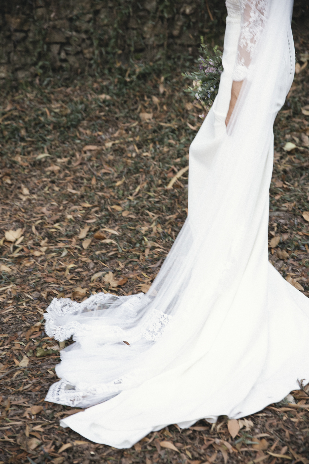 Detalle de la cola del vestido de novia extendida sobre hojas secas