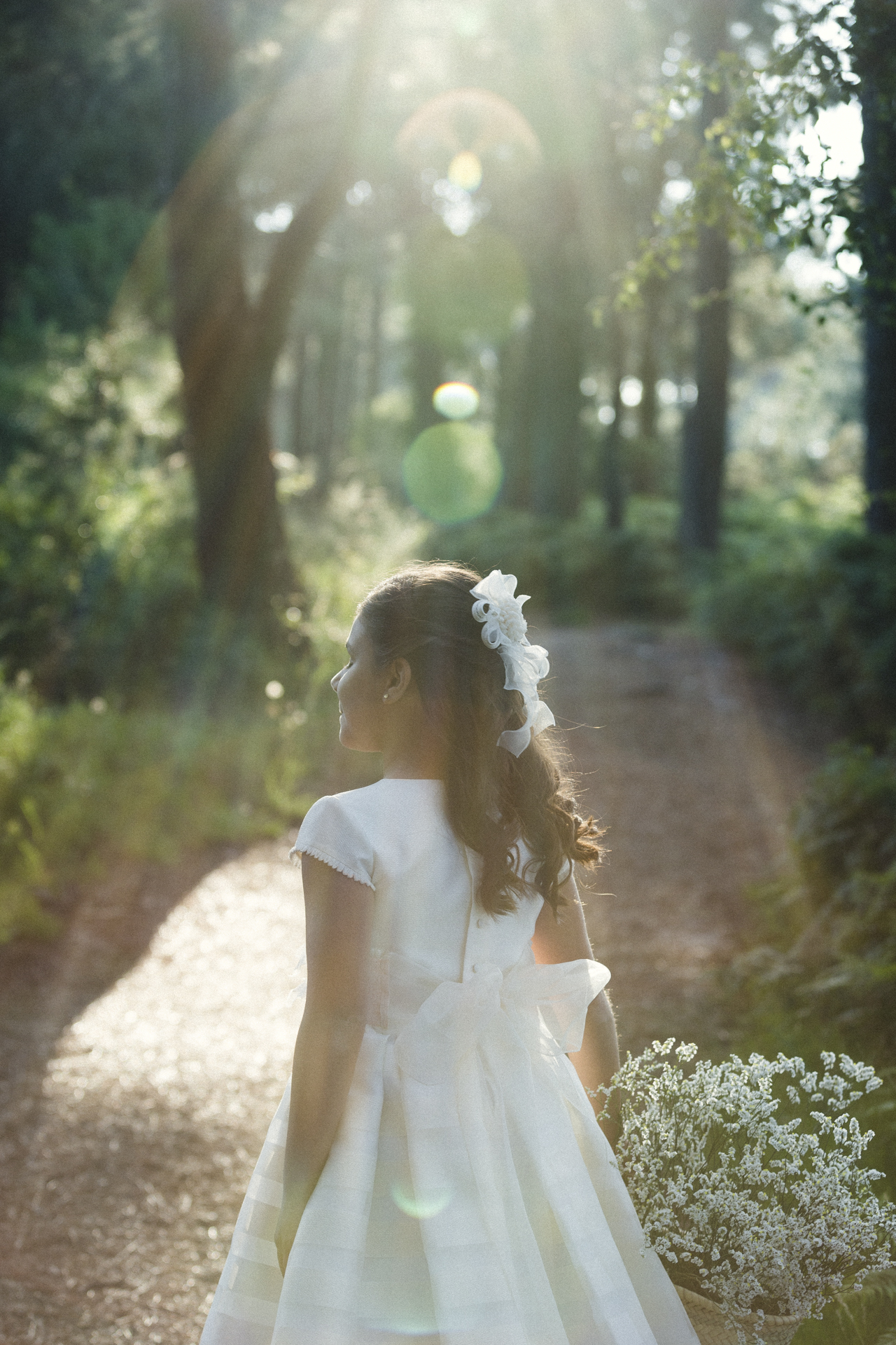 Niña de comunión caminando por un camino de bosque