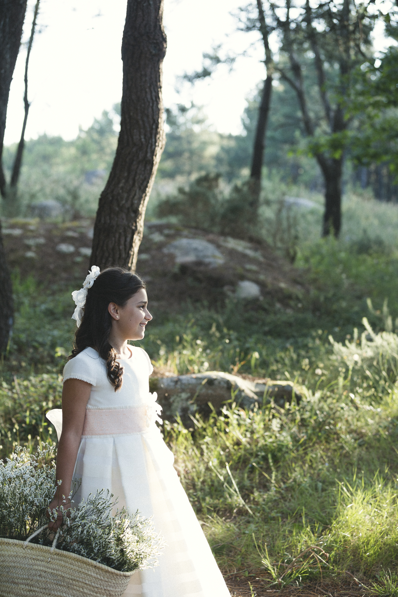 Niña de comunión de pie en el bosque con luz suave