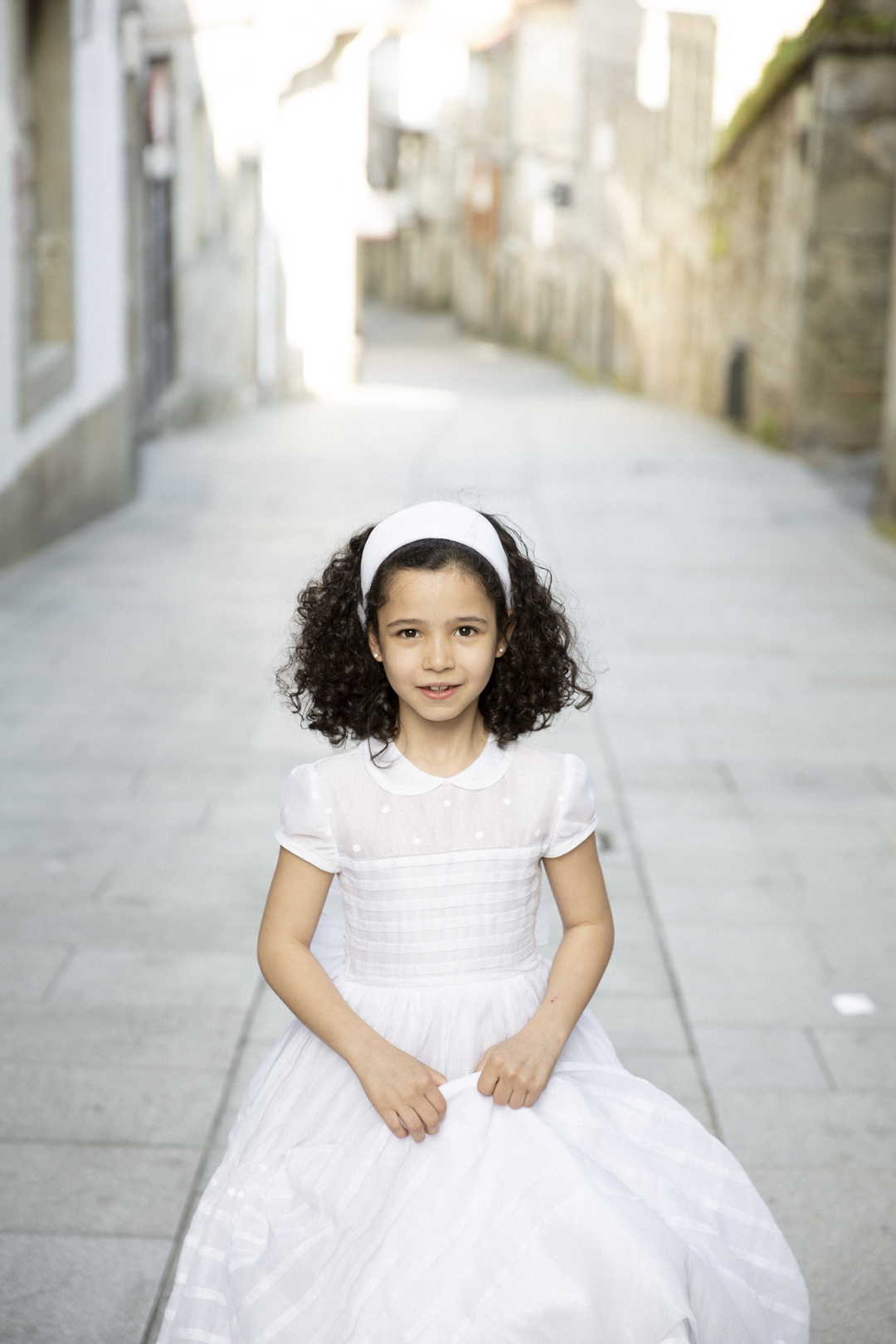 Niña de comunión de pie en una plaza del casco antiguo