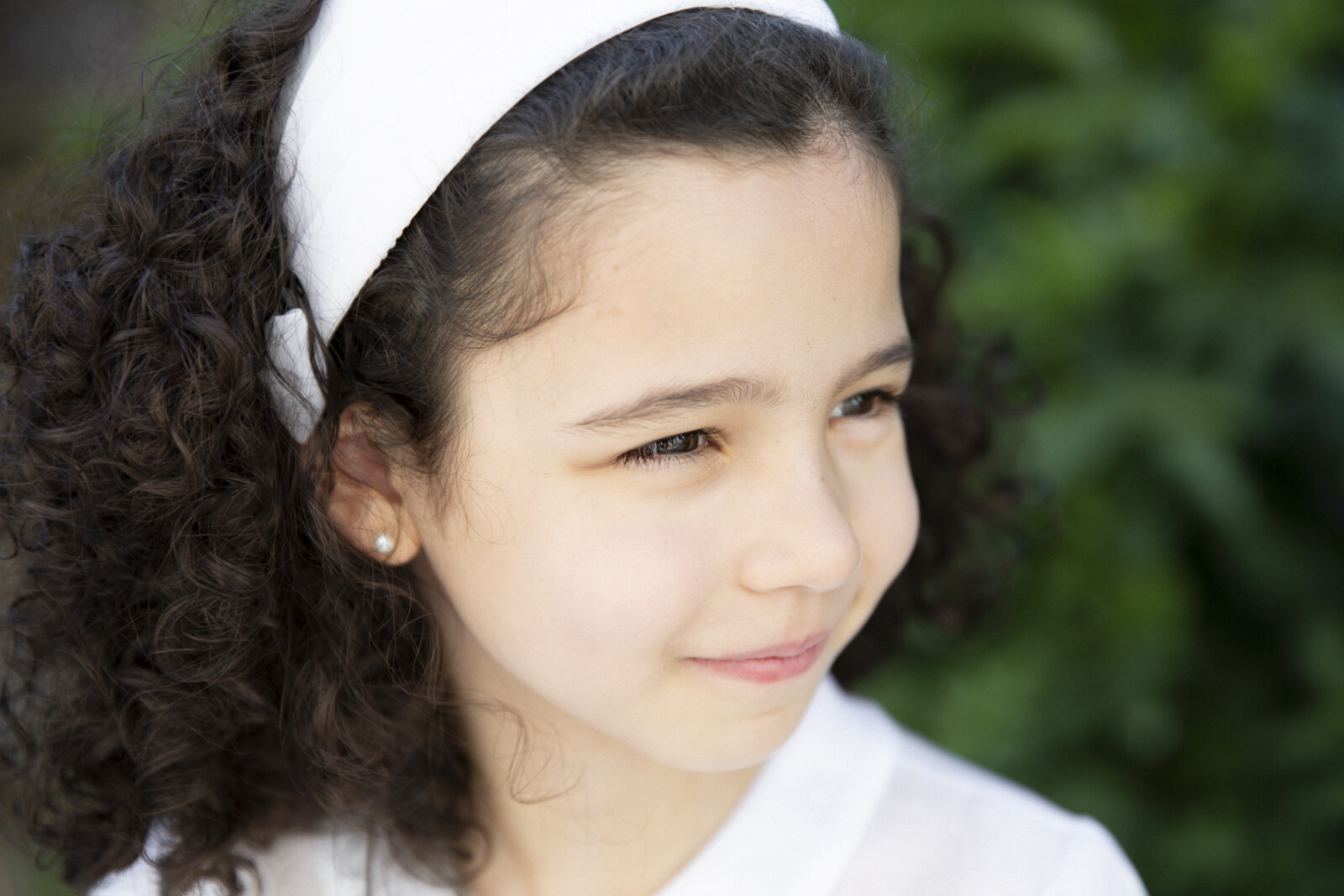 Retrato de niña sonriendo suavemente el día de su comunión