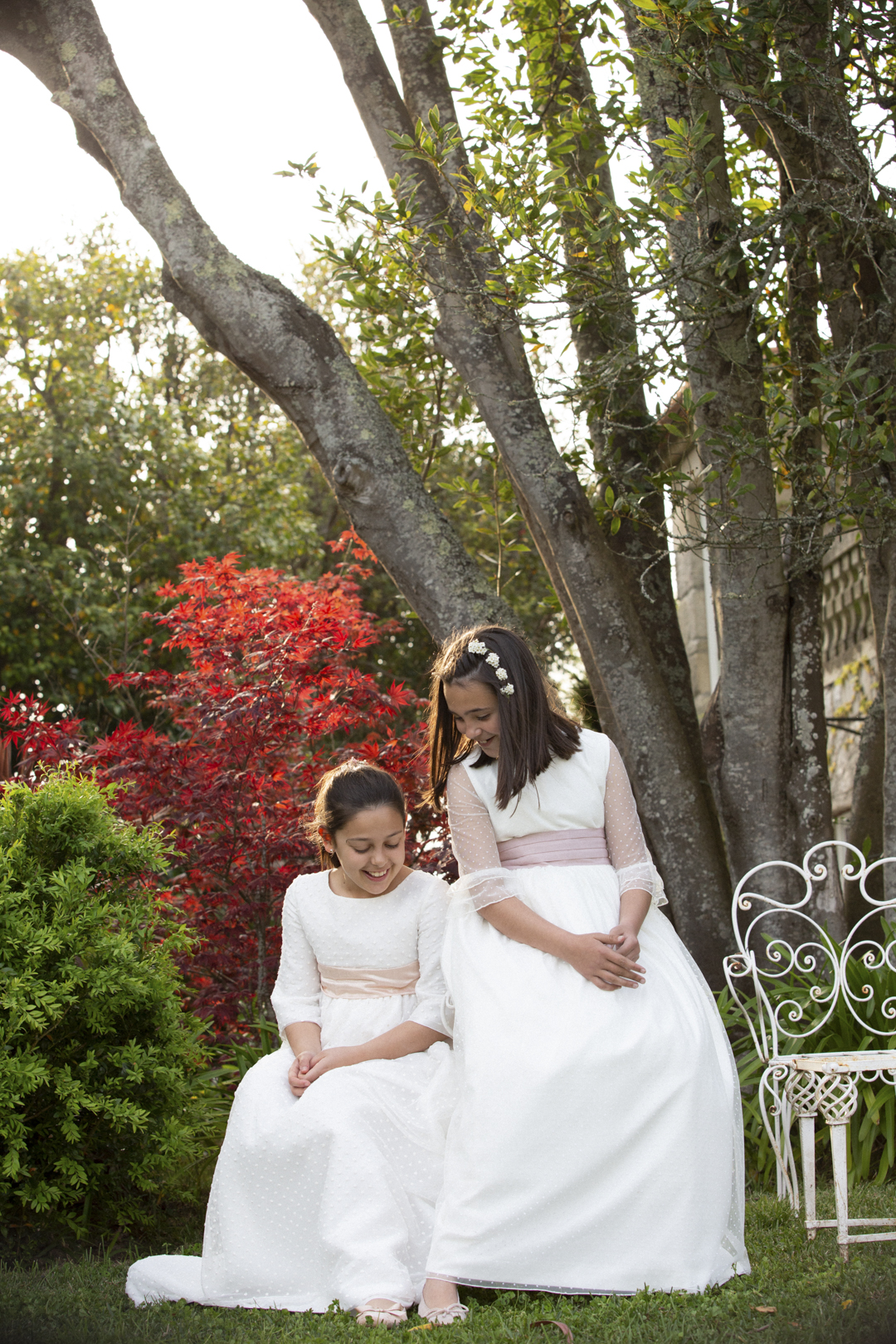Niñas con vestido de comunión sentadas en un jardín