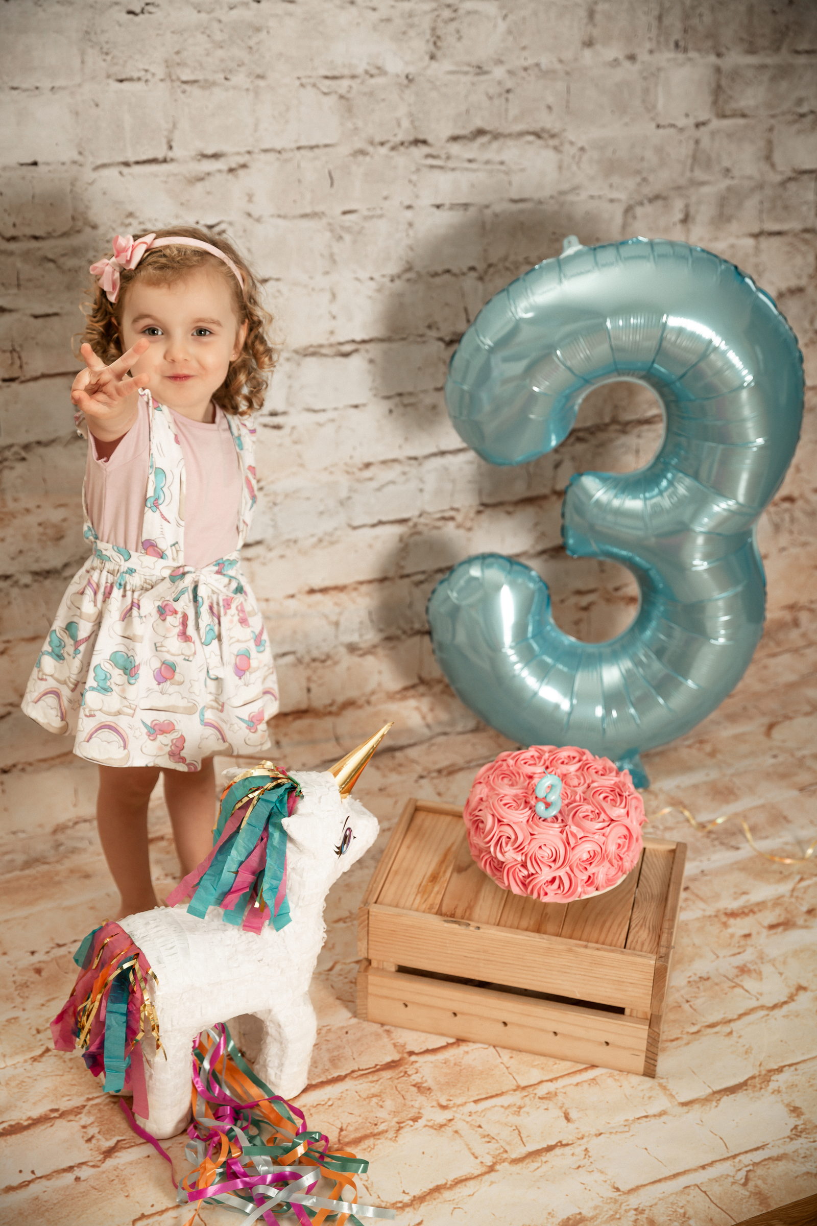 Niña con el globo del número tres y su tarta de cumpleaños