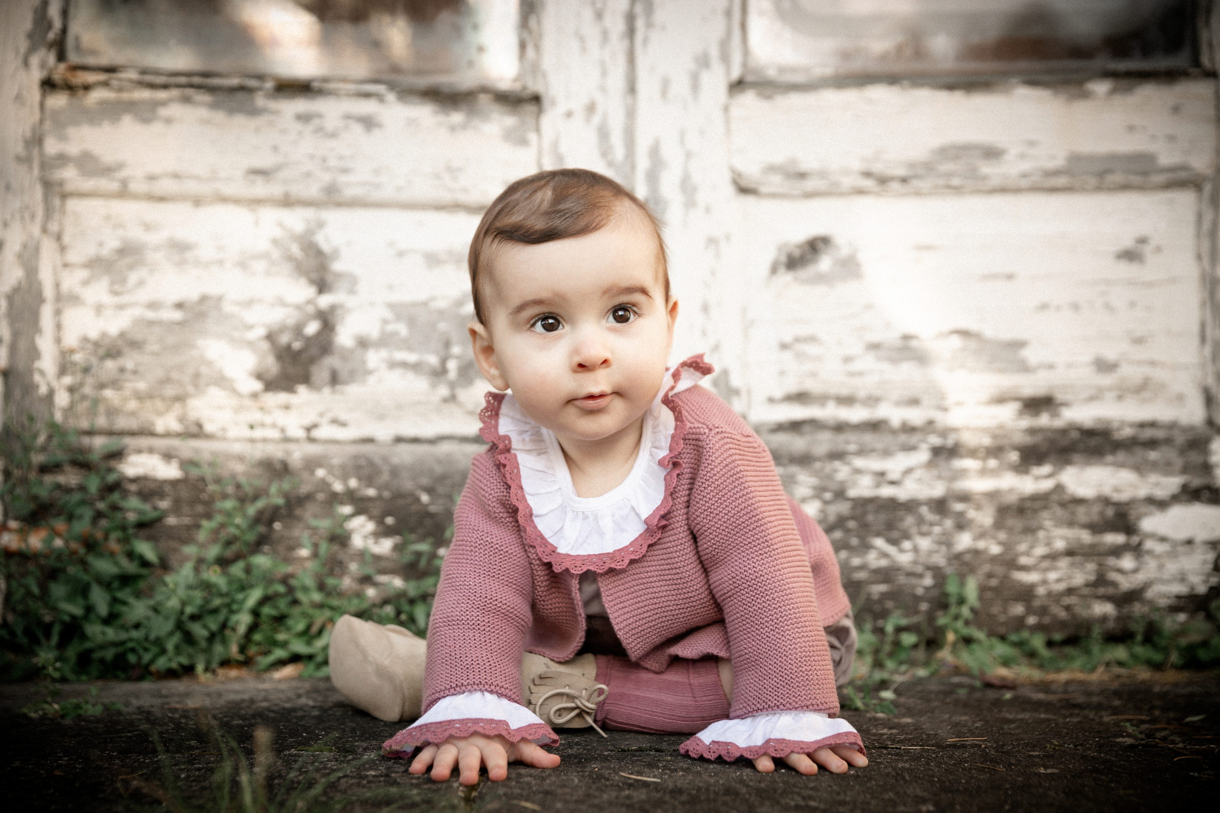 Niña gateando delante de un muro de piedra