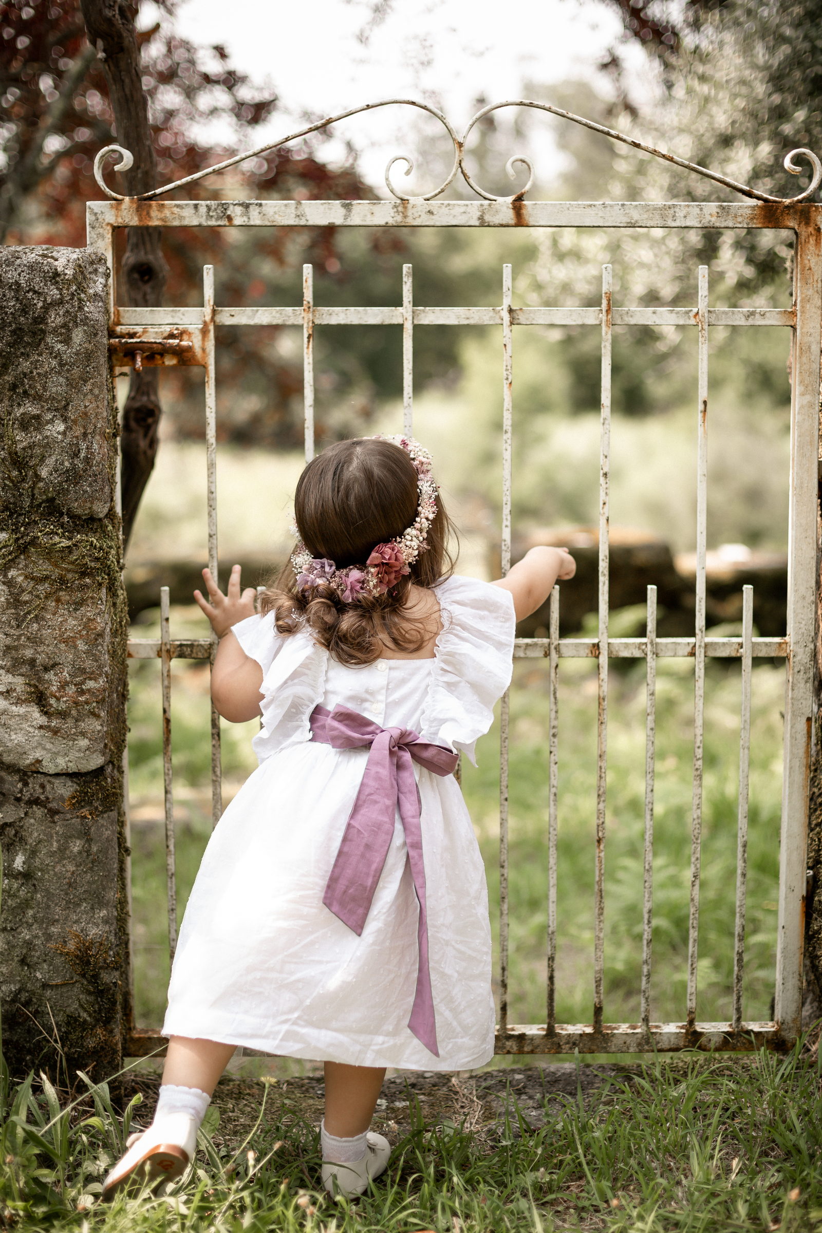 Niña asomada a una cancela de hierro de una finca gallega