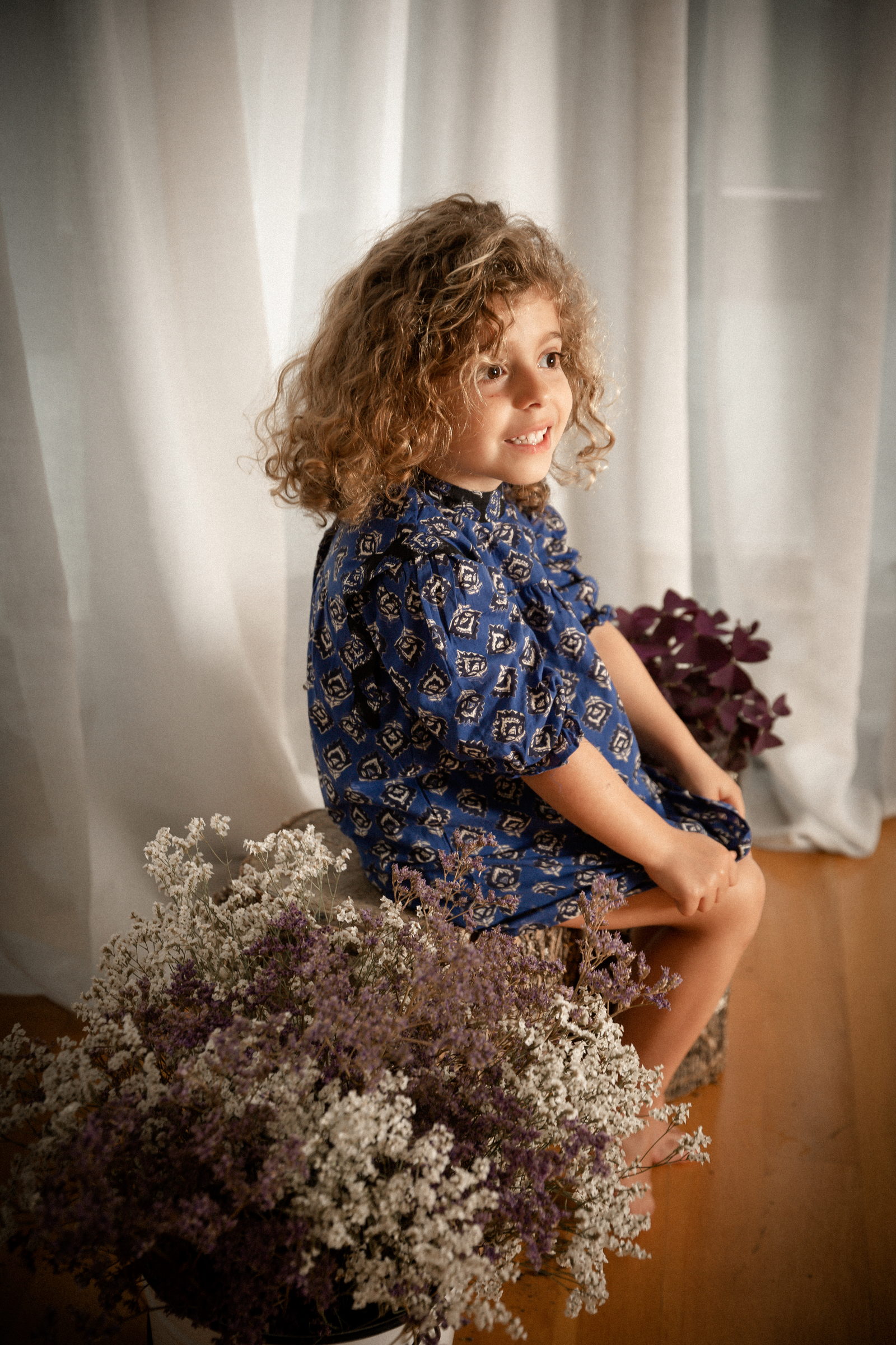 Niña de perfil junto a un ramo de lilas