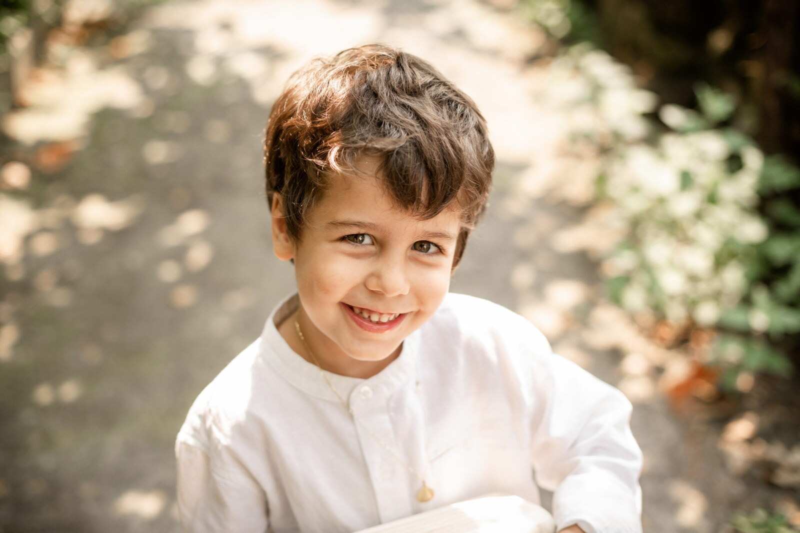 Niño sonriendo entre los árboles del jardín