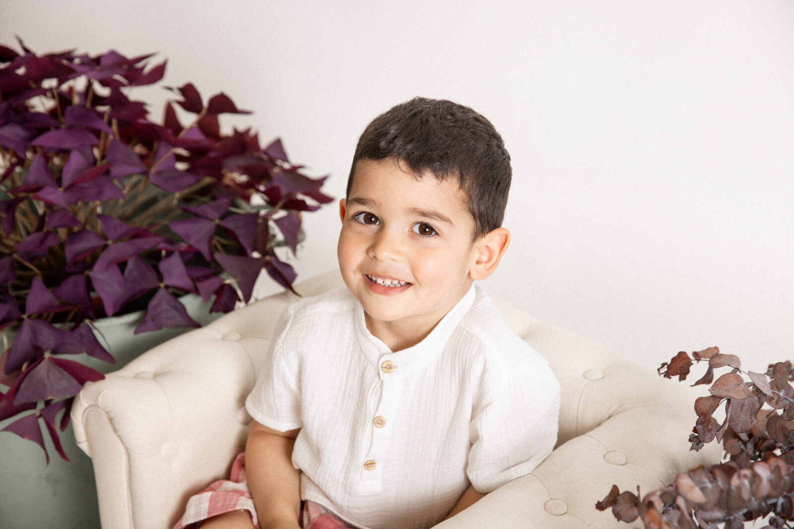 Niño sonriendo sentado en un sofá blanco