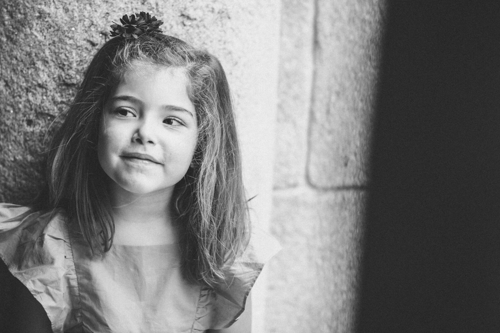 Retrato de niña en blanco y negro junto a un muro