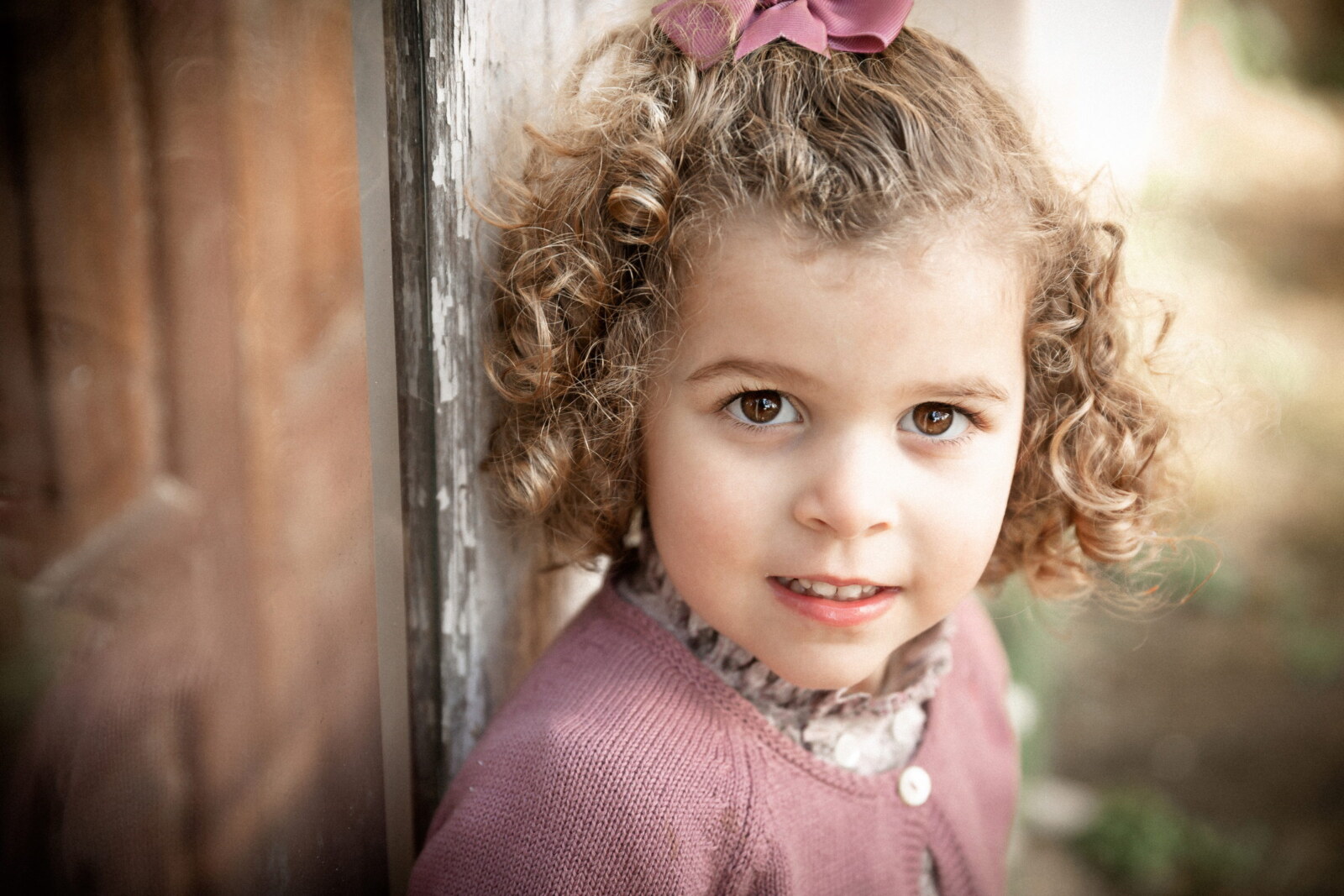 Retrato cercano de una niña de rizos con jersey rosa