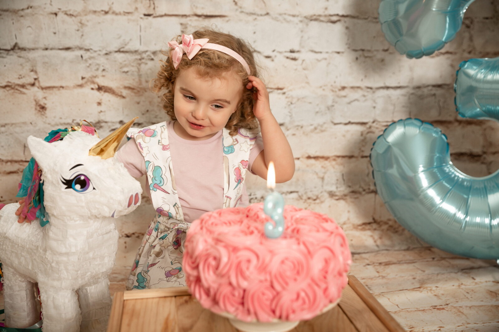 Niña con su tarta de cumpleaños y un unicornio de juguete