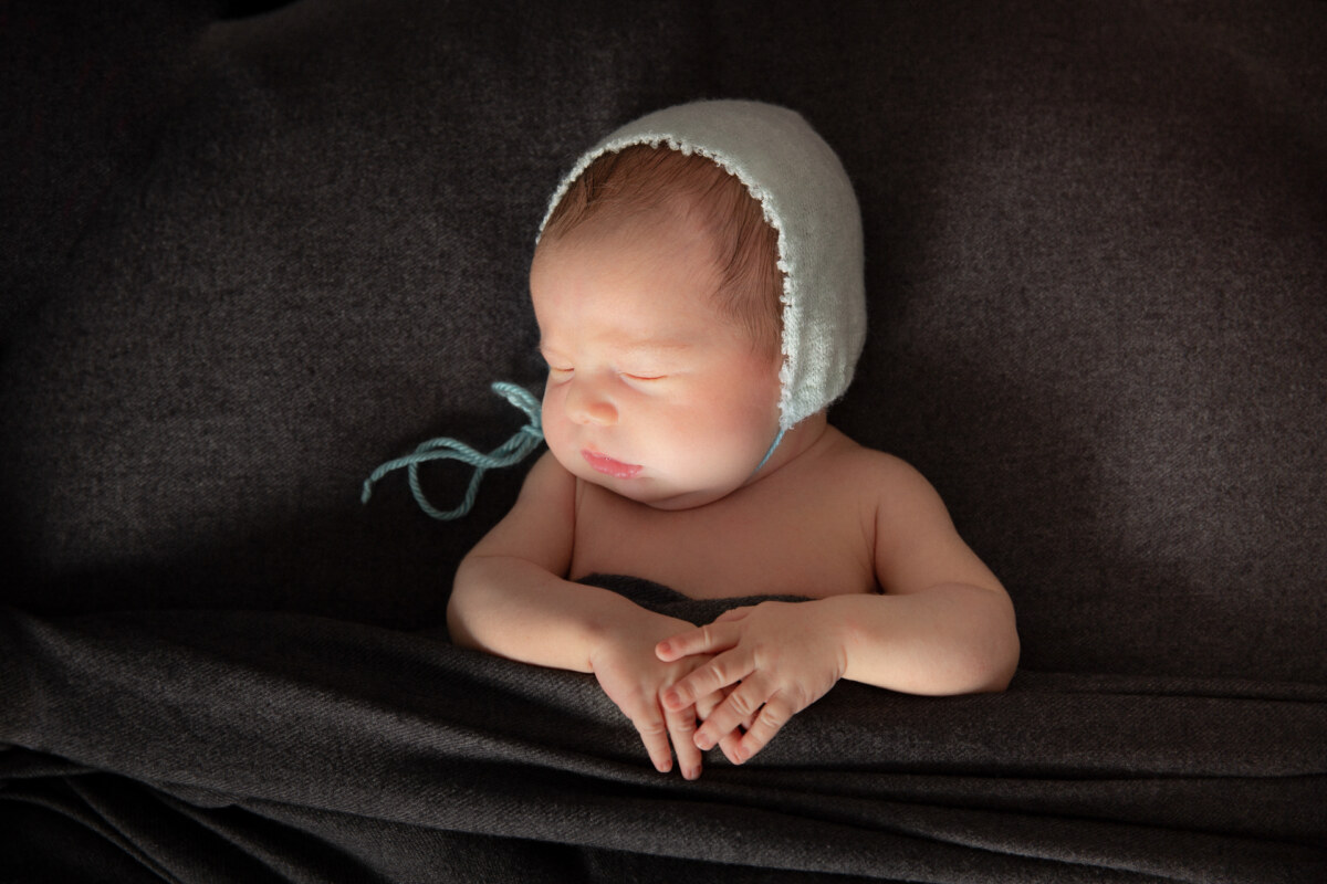 Bebé con gorrito de punto y manos entrelazadas, fotografía newborn en Pontevedra