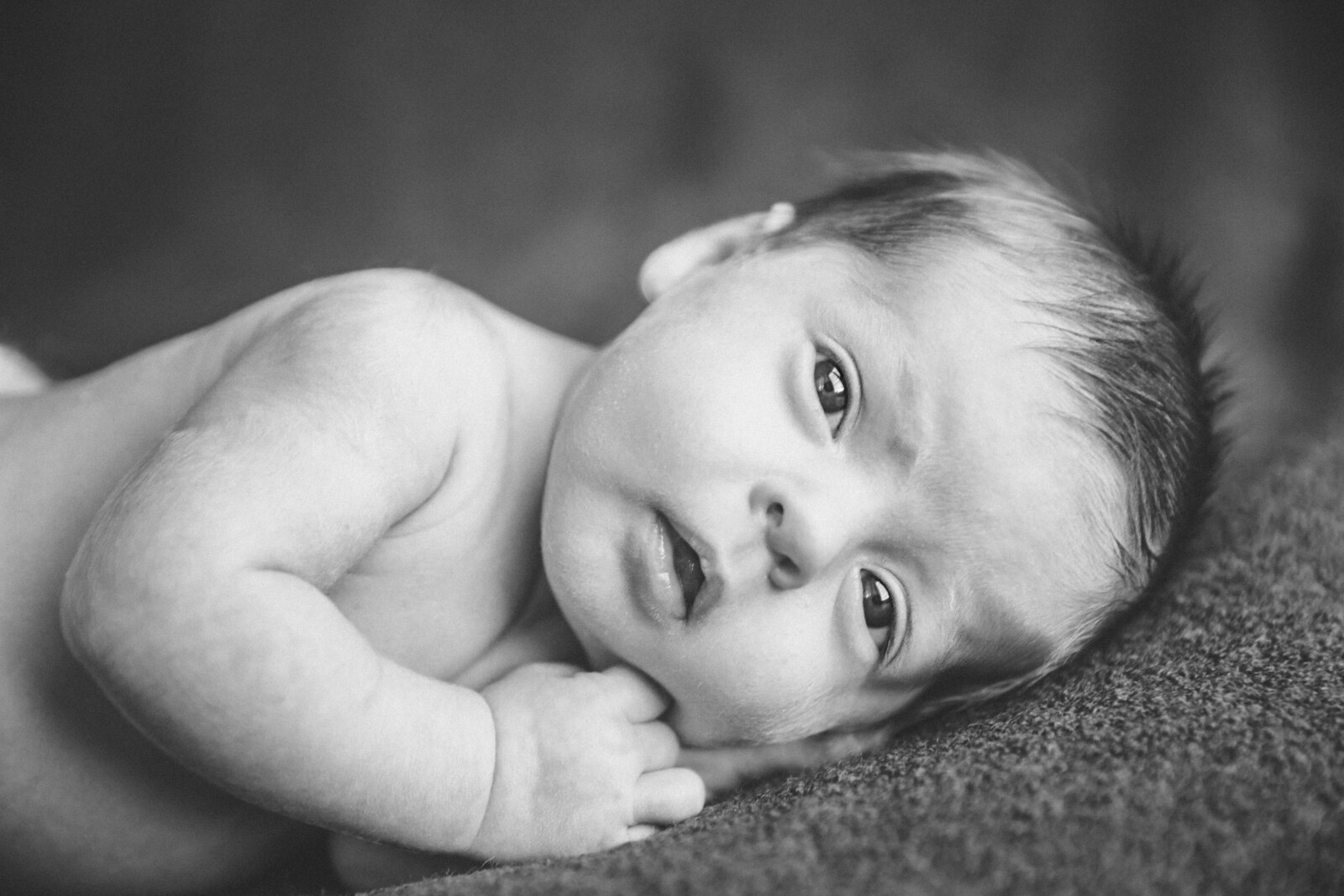 Retrato en blanco y negro de un recién nacido despierto sobre una manta