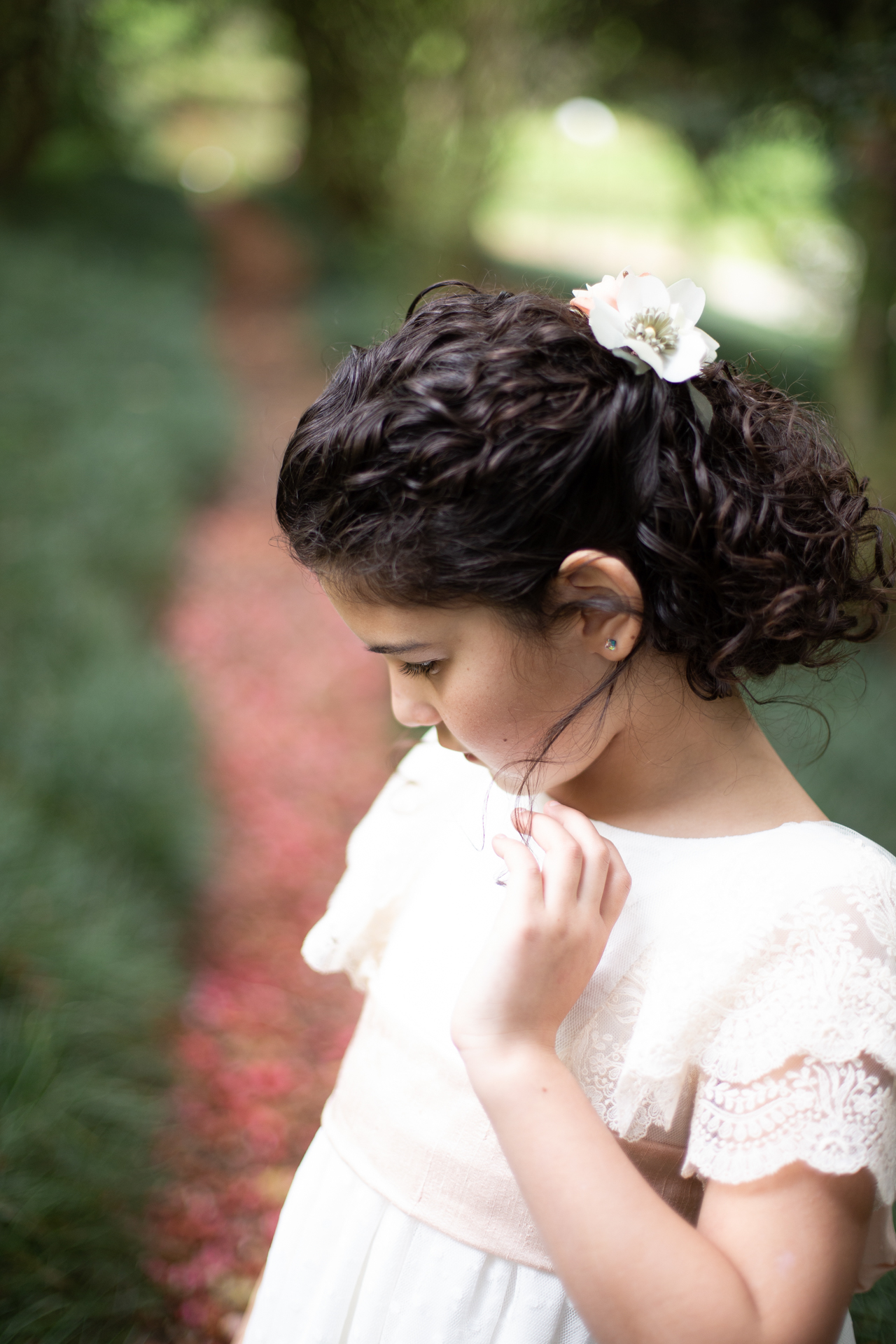 Niña de comunión en un camino con pétalos rosas