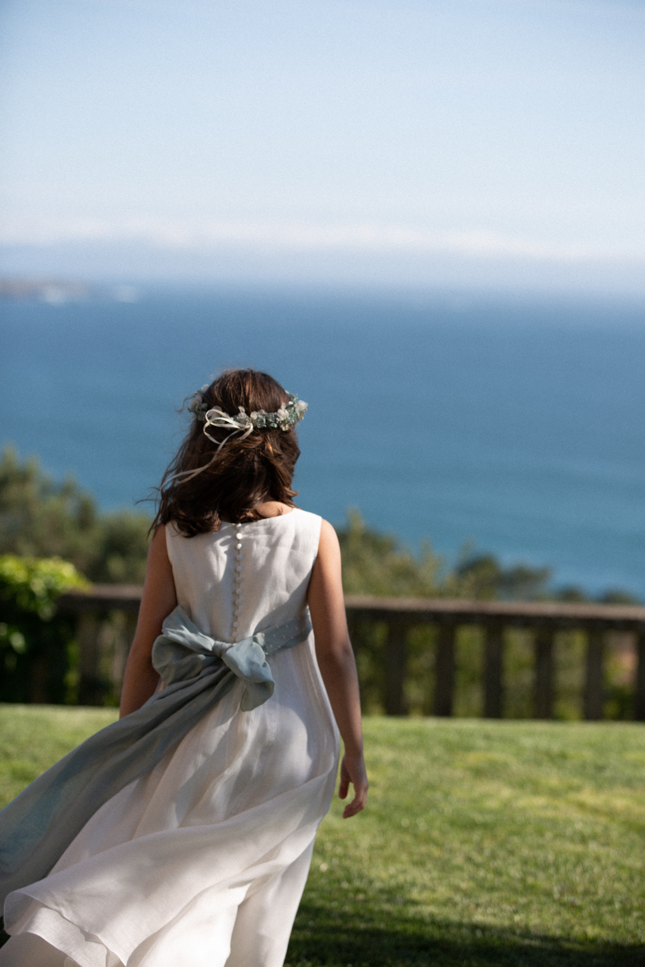 Niña de comunión caminando en una terraza con vistas al mar
