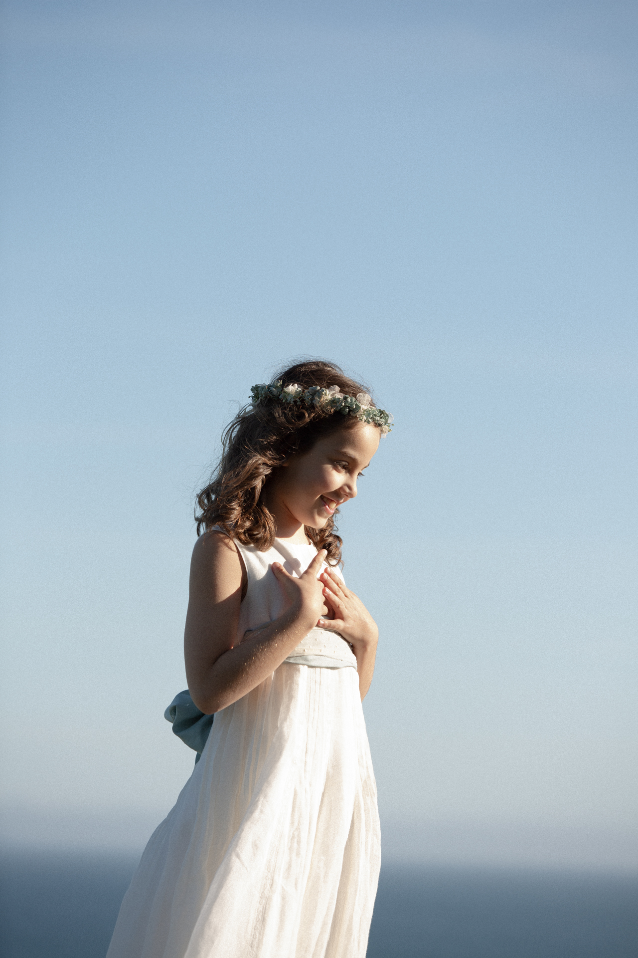 Niña de comunión junto al mar con el pelo al viento