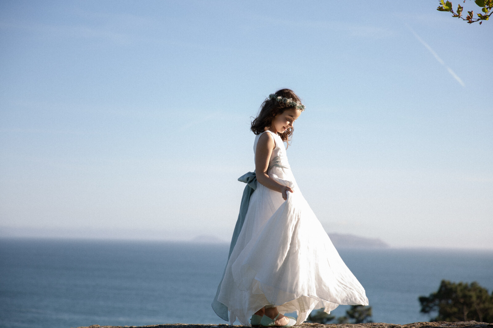 Niña con corona de flores frente al mar el día de su comunión