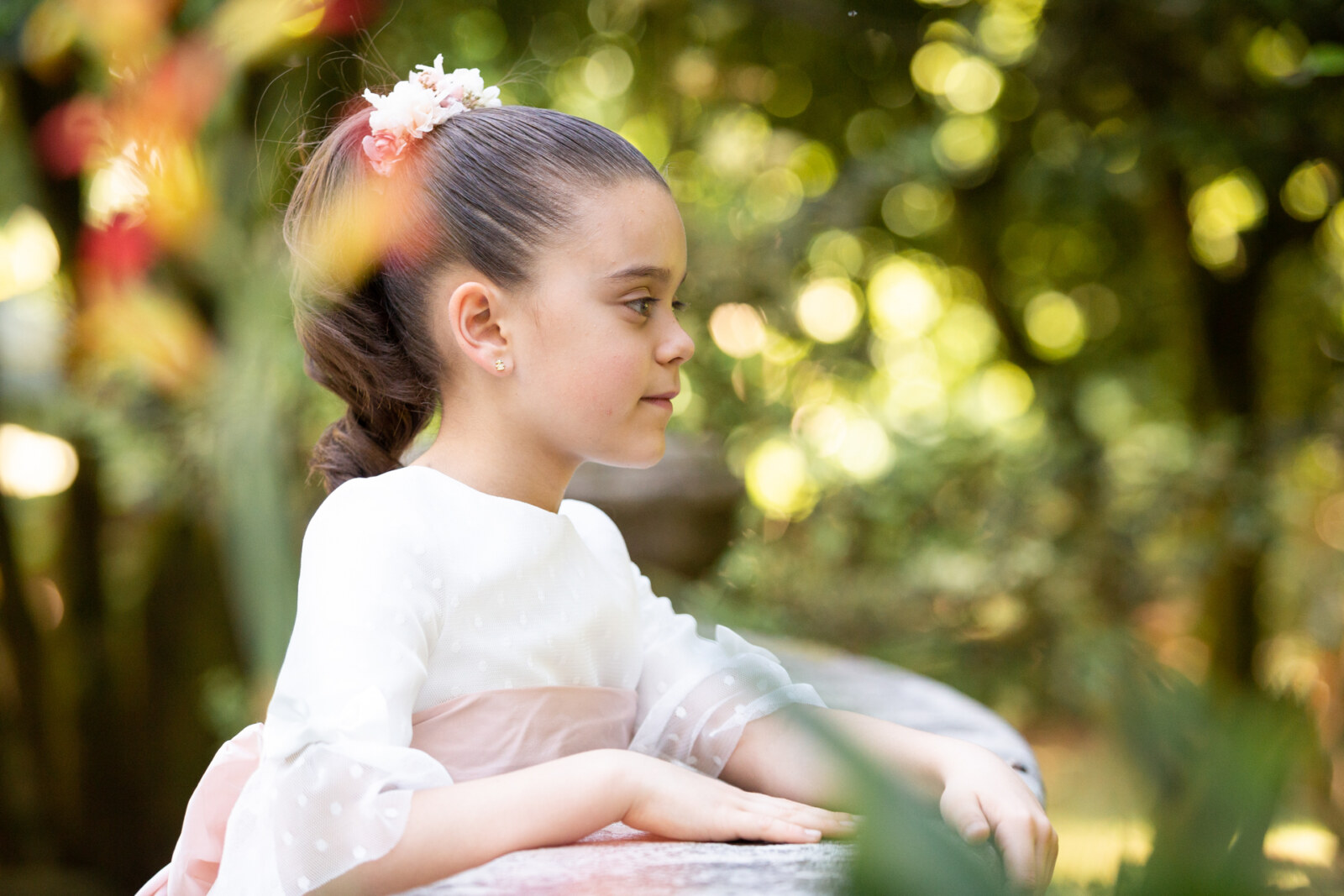 Retrato de niña de comunión sentada en el jardín