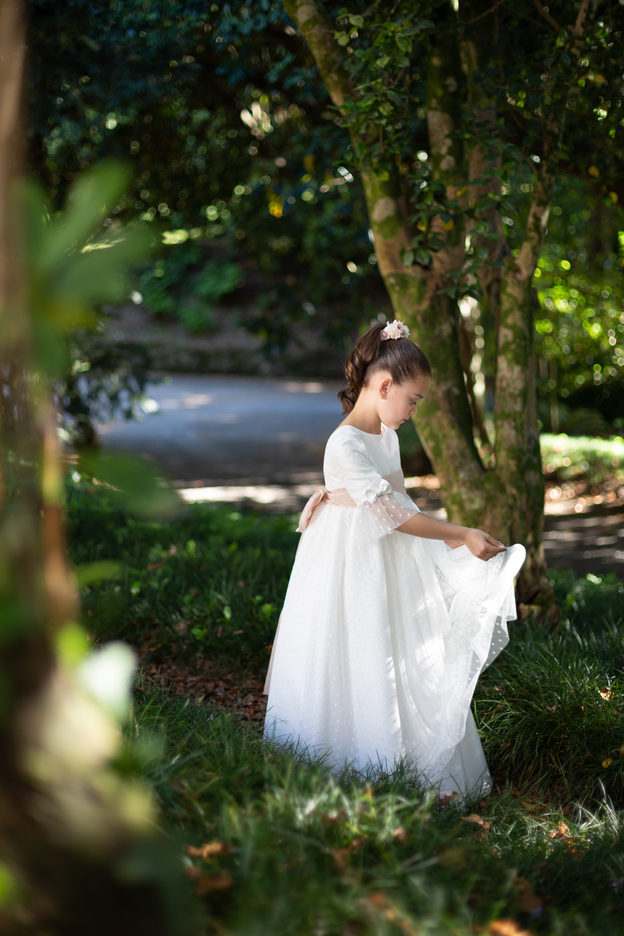 Niña de comunión ajustándose la falda en el bosque