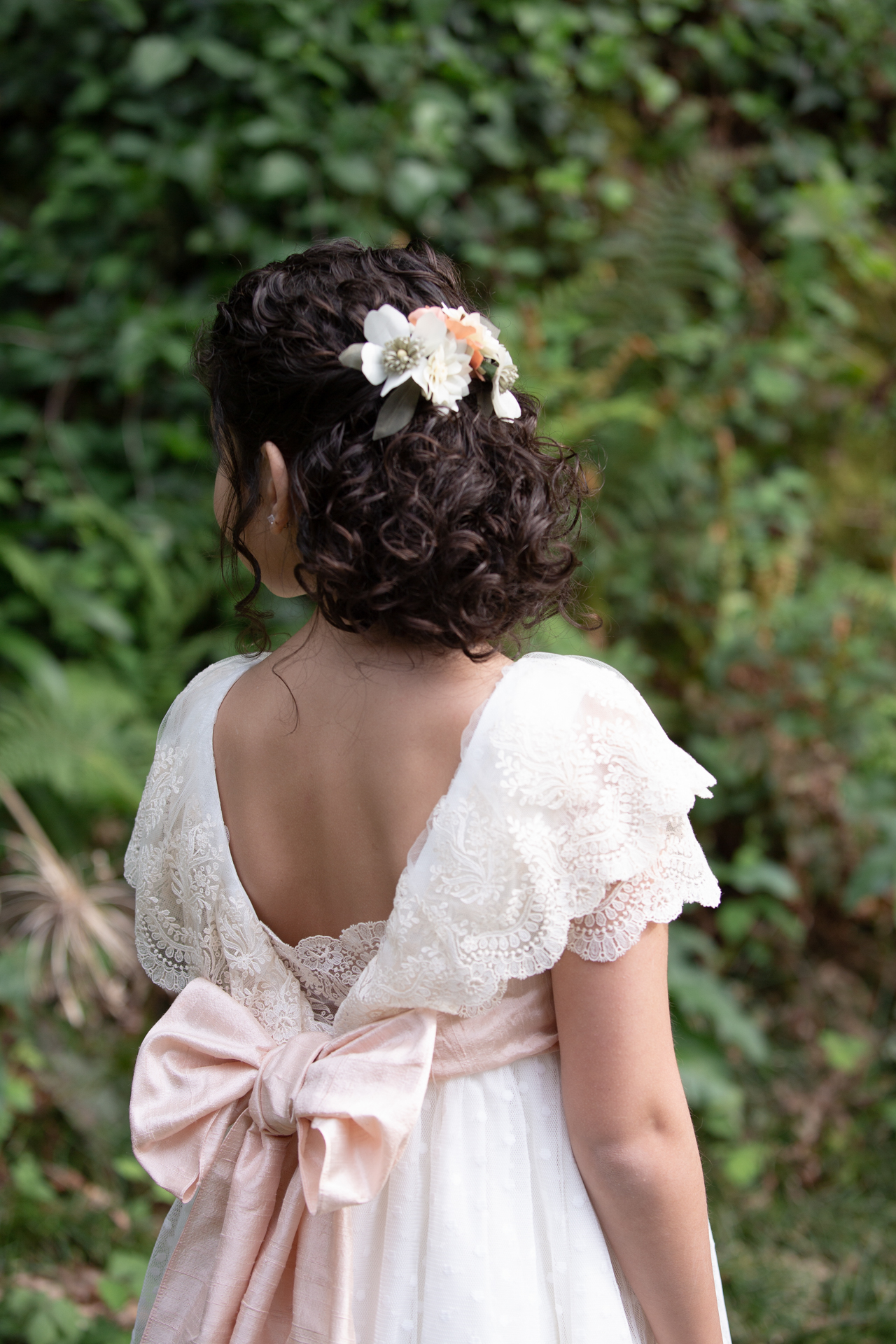 Niña de comunión de espaldas con flores en el pelo
