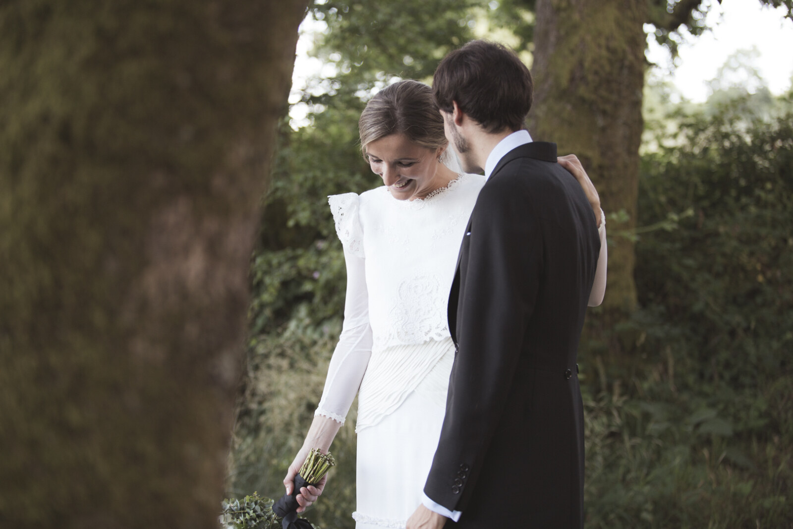 Novios abrazados bajo los árboles al atardecer, fotografía de boda en Pontevedra