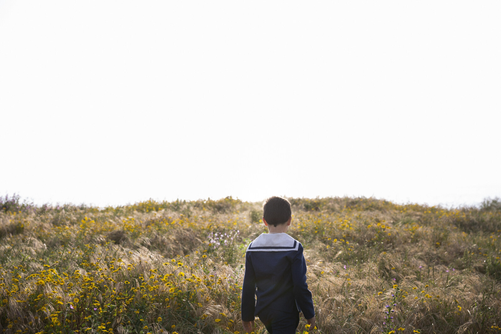 Niño de comunión caminando por un campo abierto en Sanxenxo